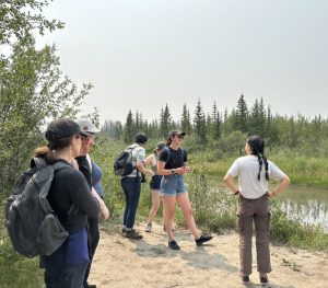 A group of people standing and talking near a river.
